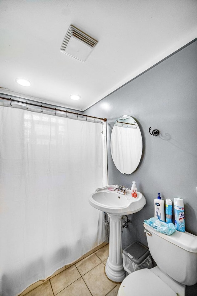 bathroom with curtained shower, toilet, and tile patterned flooring