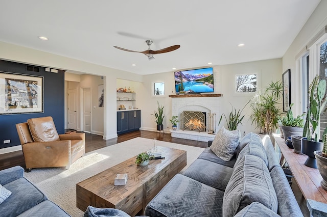 living room with hardwood / wood-style flooring, a brick fireplace, and ceiling fan