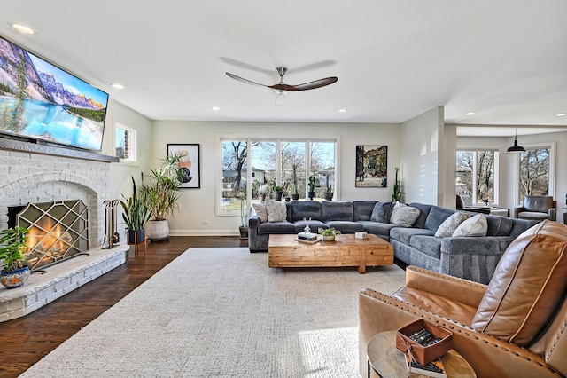 living room featuring a brick fireplace, dark hardwood / wood-style flooring, and ceiling fan