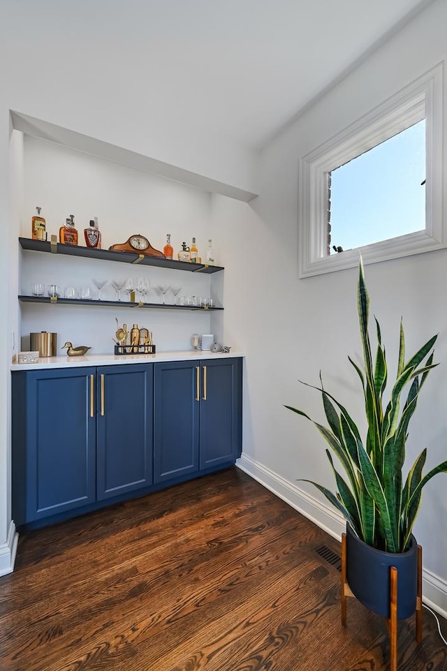 bar featuring blue cabinets and dark wood-type flooring