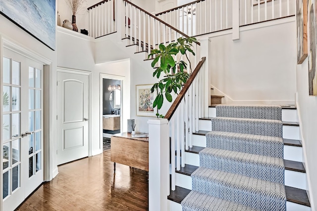 foyer featuring french doors, wood-type flooring, and a towering ceiling