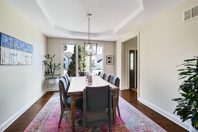 dining area featuring dark hardwood / wood-style floors and a raised ceiling