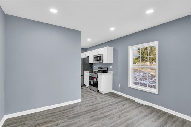 kitchen with stainless steel appliances, light hardwood / wood-style flooring, and white cabinets