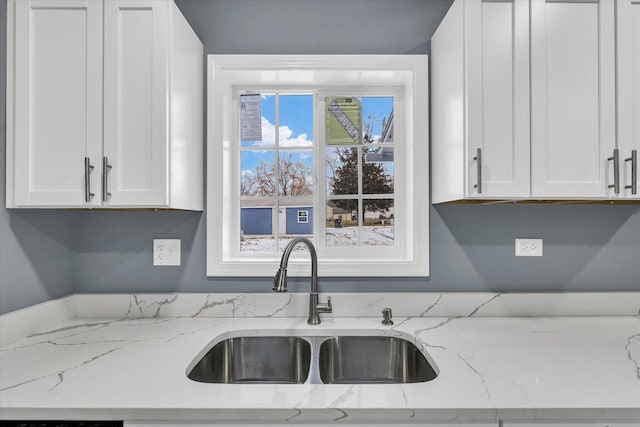 kitchen featuring white cabinets, sink, and light stone counters