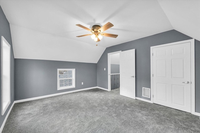 bonus room with lofted ceiling, ceiling fan, and dark colored carpet