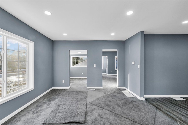 unfurnished room with dark colored carpet and plenty of natural light