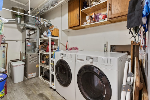 laundry room with independent washer and dryer, wood-type flooring, and cabinets