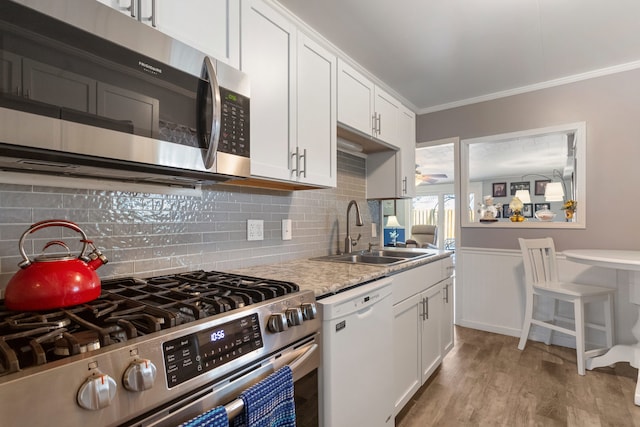 kitchen with white cabinetry, appliances with stainless steel finishes, sink, and crown molding