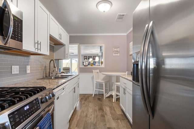 kitchen with white cabinetry, stainless steel appliances, sink, and light wood-type flooring