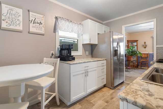 kitchen with stainless steel refrigerator with ice dispenser, sink, white cabinets, and light hardwood / wood-style floors