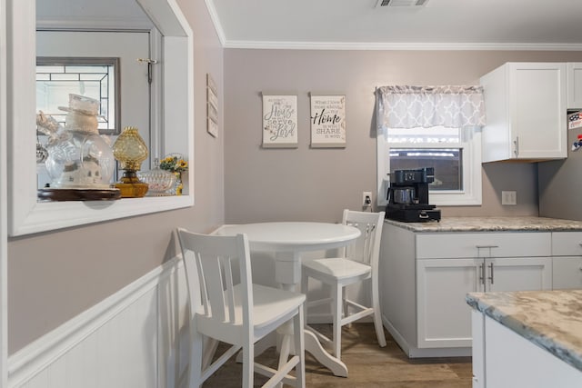 dining space with crown molding and light hardwood / wood-style flooring