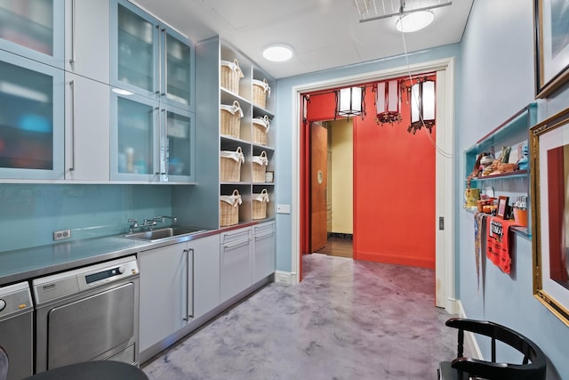 kitchen with hanging light fixtures, dishwashing machine, sink, and separate washer and dryer