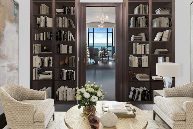 sitting room with a water view, wood-type flooring, a chandelier, and lofted ceiling