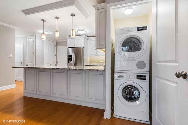 laundry area with hardwood / wood-style flooring, ornamental molding, and stacked washer / drying machine