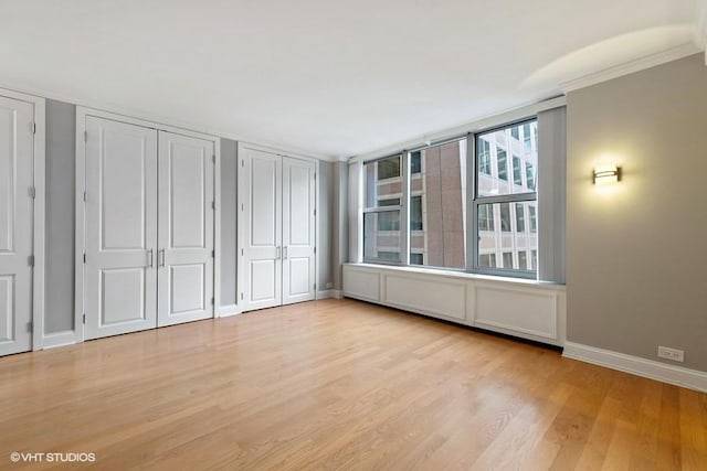 unfurnished bedroom with light hardwood / wood-style floors and multiple closets