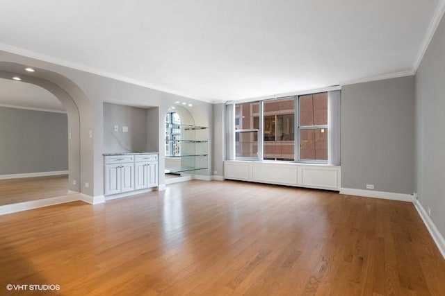 spare room with ornamental molding and light wood-type flooring