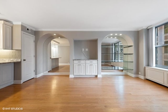 unfurnished dining area featuring crown molding and light hardwood / wood-style flooring