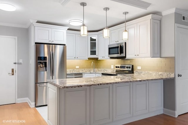 kitchen with white cabinetry, kitchen peninsula, stainless steel appliances, light stone countertops, and backsplash