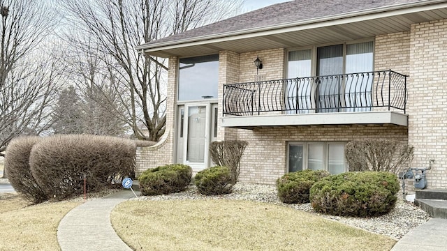 property entrance with a balcony and brick siding