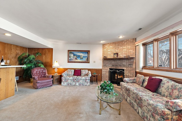 living room featuring carpet, a wainscoted wall, visible vents, a brick fireplace, and wood walls