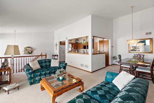 carpeted living area featuring baseboards, a high ceiling, visible vents, and a notable chandelier