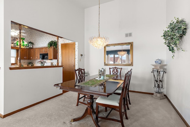 dining area featuring light carpet, a towering ceiling, visible vents, and an inviting chandelier