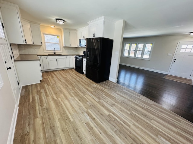 18947 Ridgewood Ave, Lansing, IL 60438 - kitchen with black fridge with ice dispenser, gas range, stainless steel microwave, dark countertops, and open floor plan