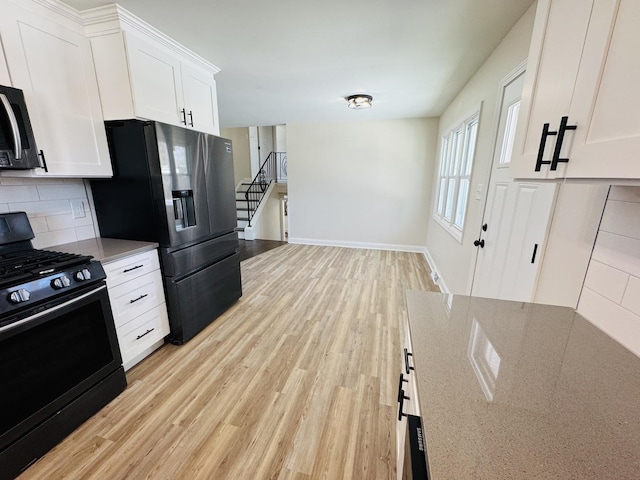 kitchen with light wood-type flooring, appliances with stainless steel finishes, decorative backsplash, and white cabinets