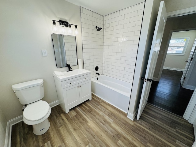 full bathroom featuring toilet, tiled shower / bath combo, vanity, and hardwood / wood-style flooring