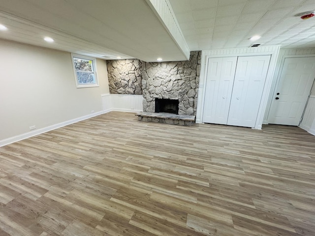 basement featuring a fireplace and light hardwood / wood-style flooring