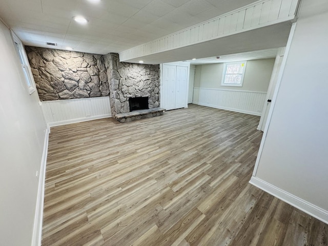 basement featuring hardwood / wood-style floors and a stone fireplace