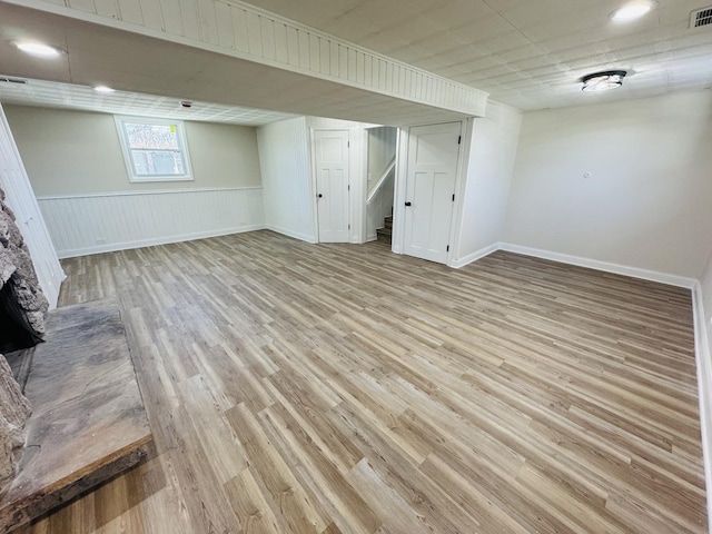 basement with a fireplace and light hardwood / wood-style flooring