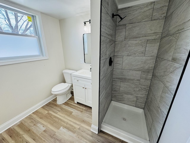 bathroom featuring vanity, toilet, hardwood / wood-style flooring, and tiled shower