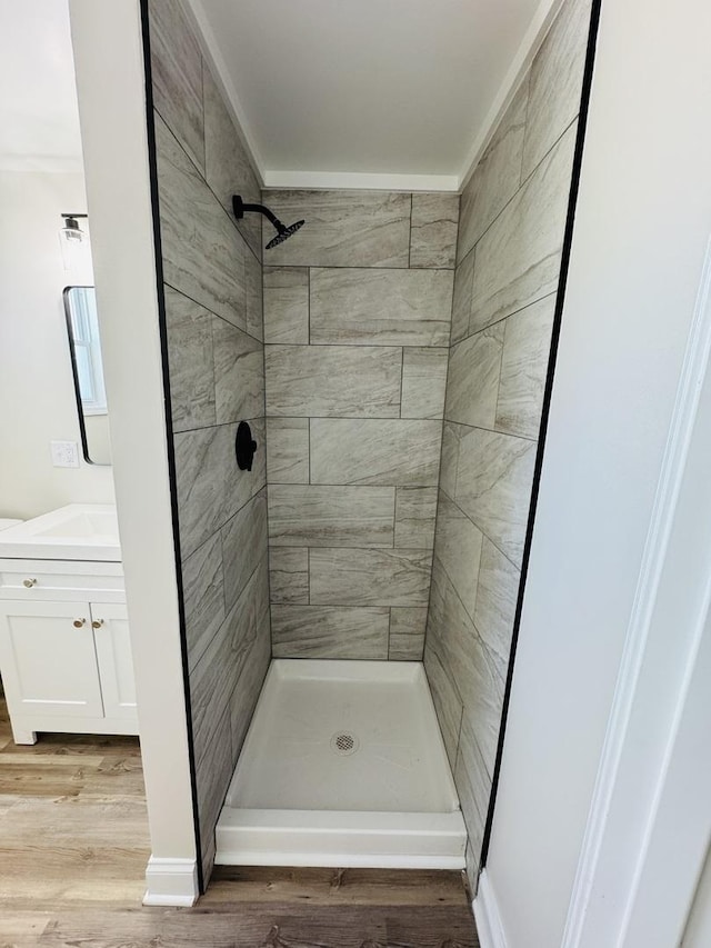 bathroom featuring hardwood / wood-style flooring, vanity, and a tile shower