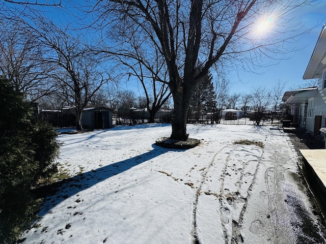 yard layered in snow with a storage shed