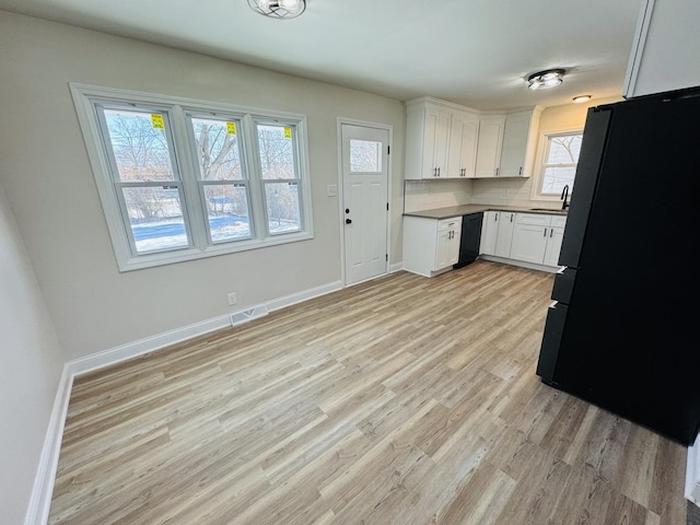 kitchen featuring white cabinetry, a healthy amount of sunlight, tasteful backsplash, and black appliances