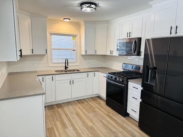 kitchen featuring light hardwood / wood-style floors, backsplash, black appliances, white cabinets, and sink