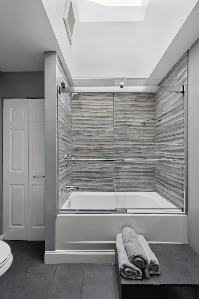 bathroom featuring toilet, tile patterned flooring, and combined bath / shower with glass door