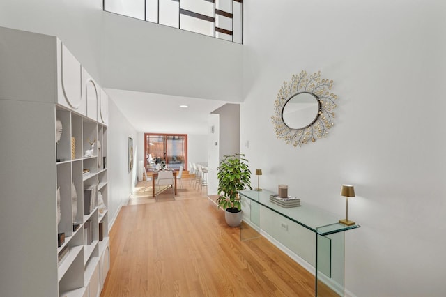 corridor featuring light hardwood / wood-style floors and a high ceiling