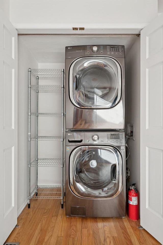 washroom featuring stacked washer and dryer and light wood-type flooring