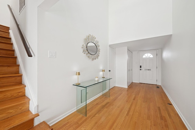 foyer with a towering ceiling and light wood-type flooring