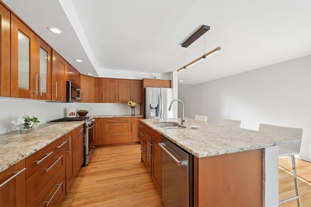 kitchen featuring sink, hanging light fixtures, a kitchen bar, stainless steel appliances, and a center island with sink