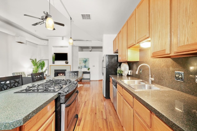 kitchen with ceiling fan, appliances with stainless steel finishes, decorative backsplash, light wood-type flooring, and sink