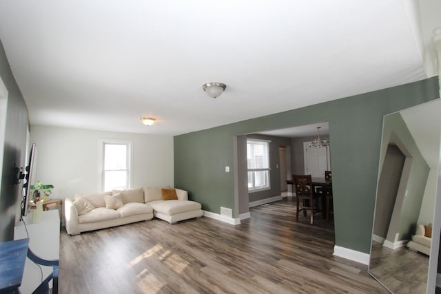 living room with an inviting chandelier, dark hardwood / wood-style floors, and a wealth of natural light