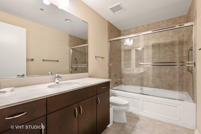 full bathroom featuring tile patterned flooring, vanity, bath / shower combo with glass door, and toilet