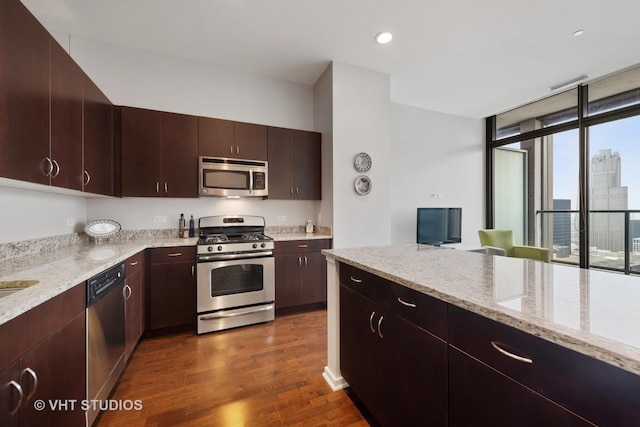 kitchen with light stone countertops, dark brown cabinets, stainless steel appliances, and dark hardwood / wood-style floors