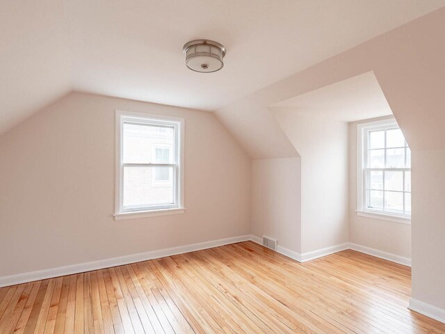 bonus room featuring a healthy amount of sunlight, vaulted ceiling, and light hardwood / wood-style flooring