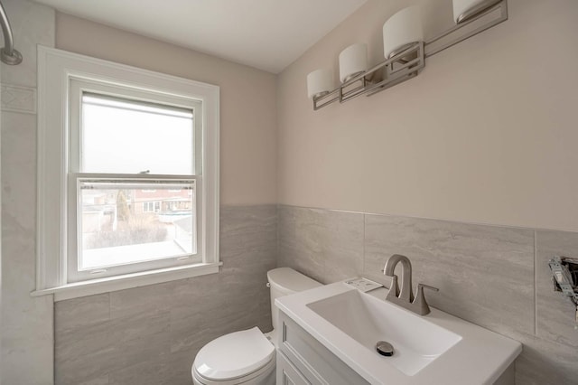 bathroom with vanity, toilet, and tile walls