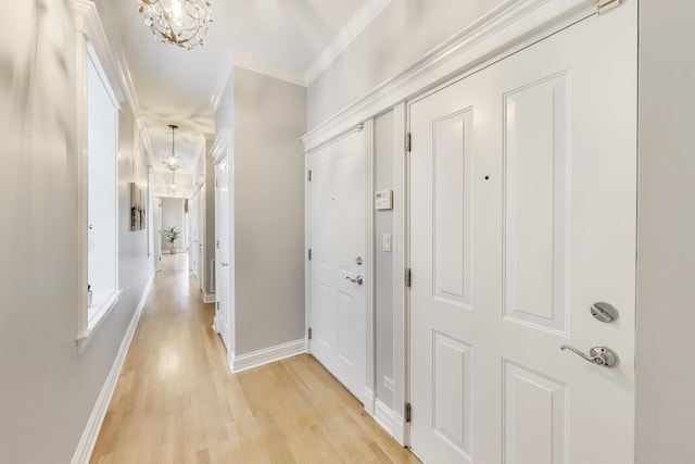 corridor featuring crown molding, a chandelier, and light hardwood / wood-style flooring