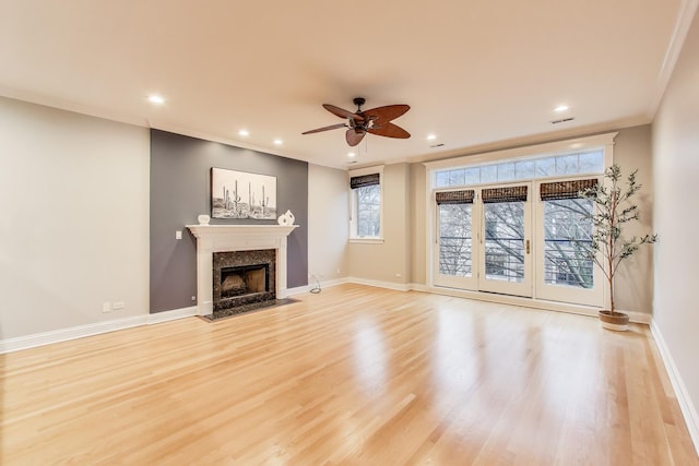 unfurnished living room featuring a fireplace, ornamental molding, ceiling fan, and light wood-type flooring